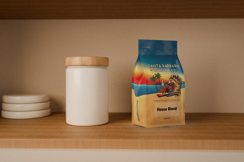 A RoCo House Blend coffee bag beside an air-tight canister on a wooden cupboard shelf.