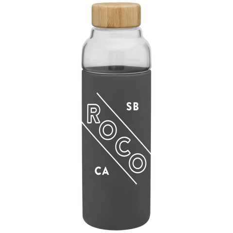 Bali 18 oz glass bottle in a dark gray sleeve printed "RoCo SB CA," with a wood lid