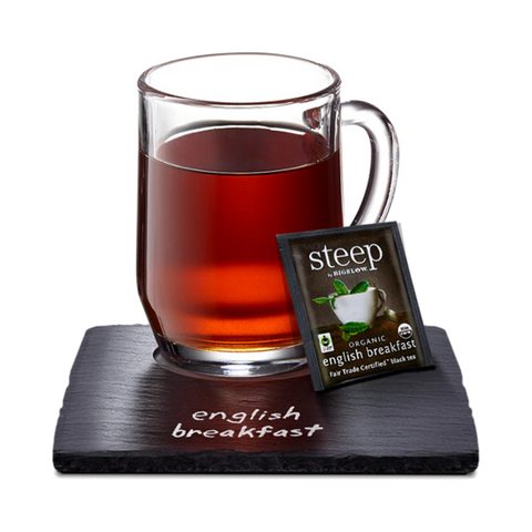 Glass mug of dark English Breakfast tea with a Steep tea bag on a slate coaster