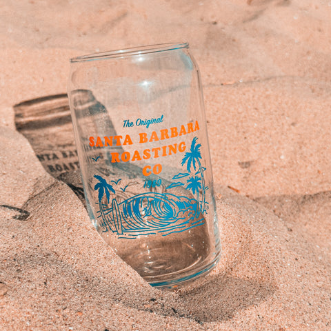 Glass can tumbler resting in warm beach sand