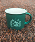Green Kindle mug sitting outdoors on pine needles